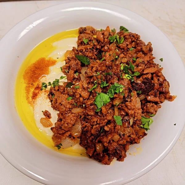 Hummus Yummy's creamy hummus topped with seasoned ground meat, olive oil, paprika, and fresh parsley.