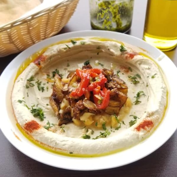Hummus Yummy's creamy hummus topped with roasted vegetables, red peppers, and fresh herbs.